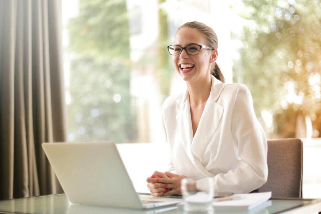 Happy employee sitting in sunny office with laptop.