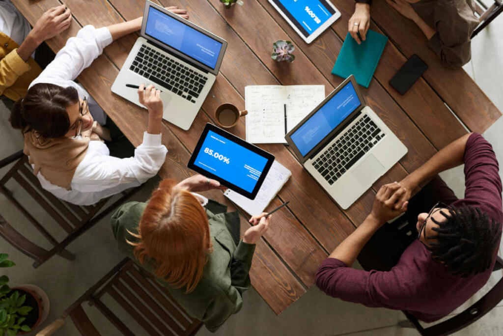 Employees working together on devices at table overhead picture.