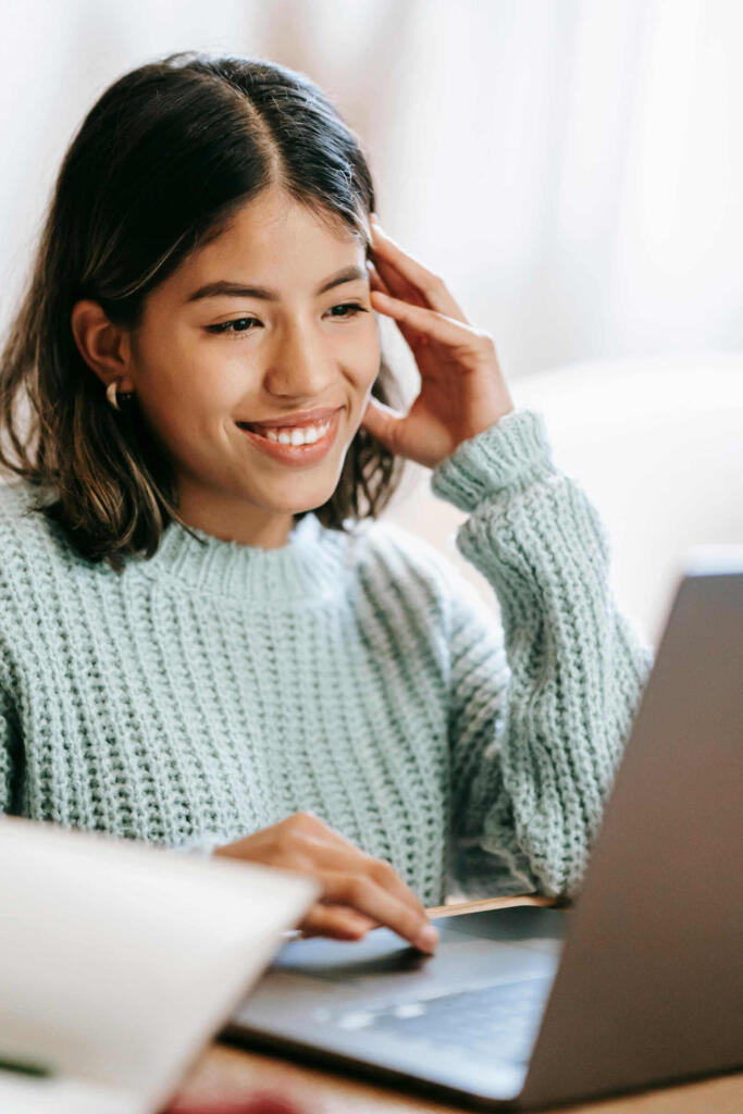 Happy young lady working on laptop.